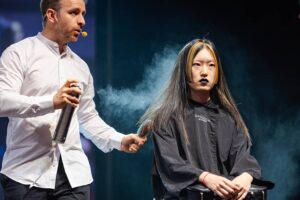 Arte in Diretta, Virtuosismo Capillare a Kadus Bologna Un maestro parrucchiere di Sassoon Academy in azione, spruzzando magia stilistica su una tela vivente durante il Kadus Event a Bologna.
