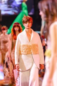 Una modella esibisce un abito ispirato al kimono con texture avvolgenti e stratificazioni audaci, una fusione perfetta di tradizione e modernità all'evento Kadus